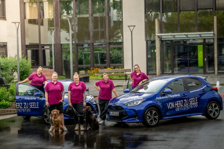 Das Team mit Dienstwägen/Firmenautos und Therapiehunden Jax und Kyla - Herz zu Seele dem Pflegedienst in Nürnberg